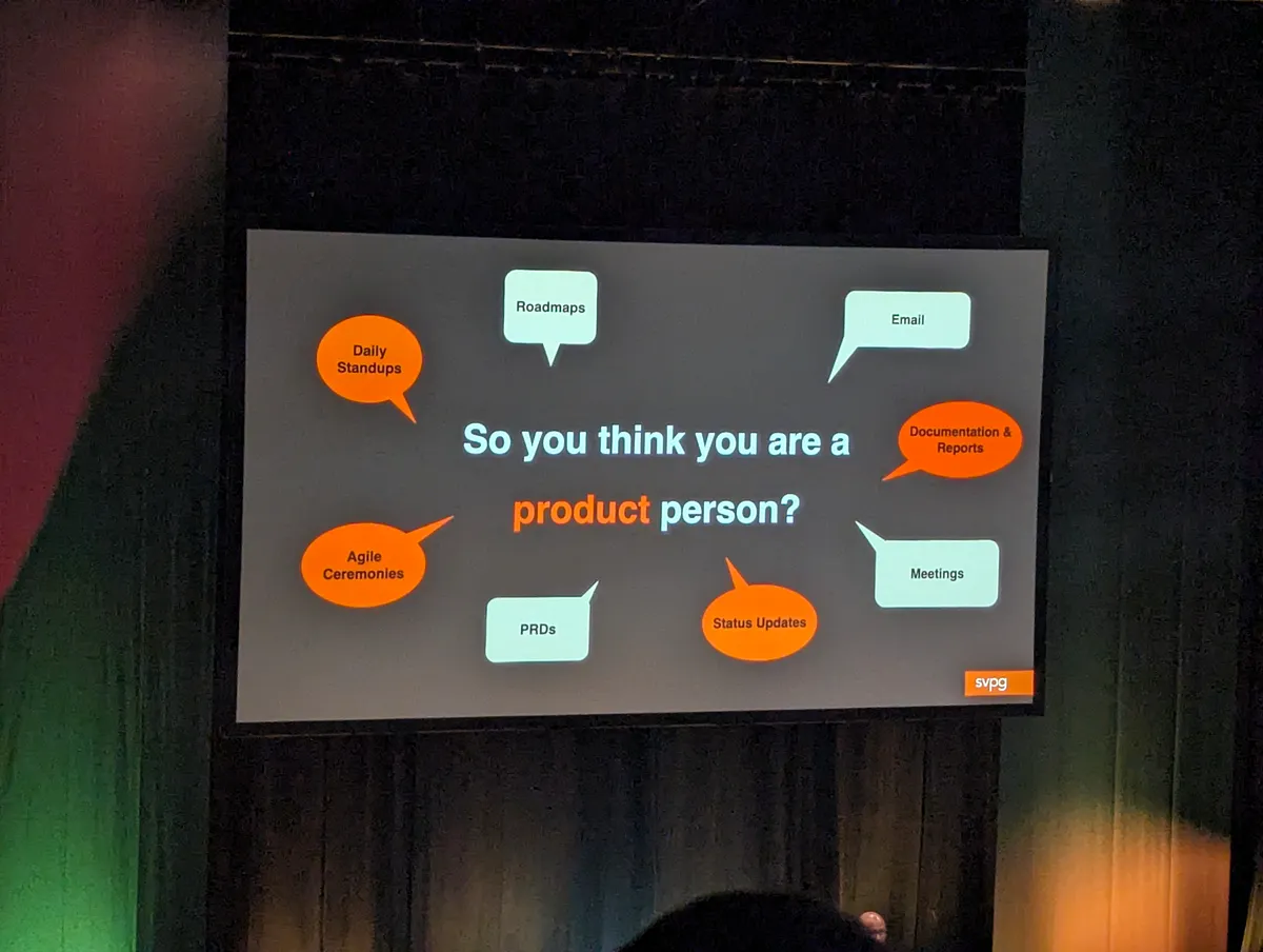 A conference slide asking "So you think you are a product person?", surrounded by speech bubbles: daily standups, roadmaps, email, documentation and reports, agile ceremonies, PRDs, status updates and meetings.